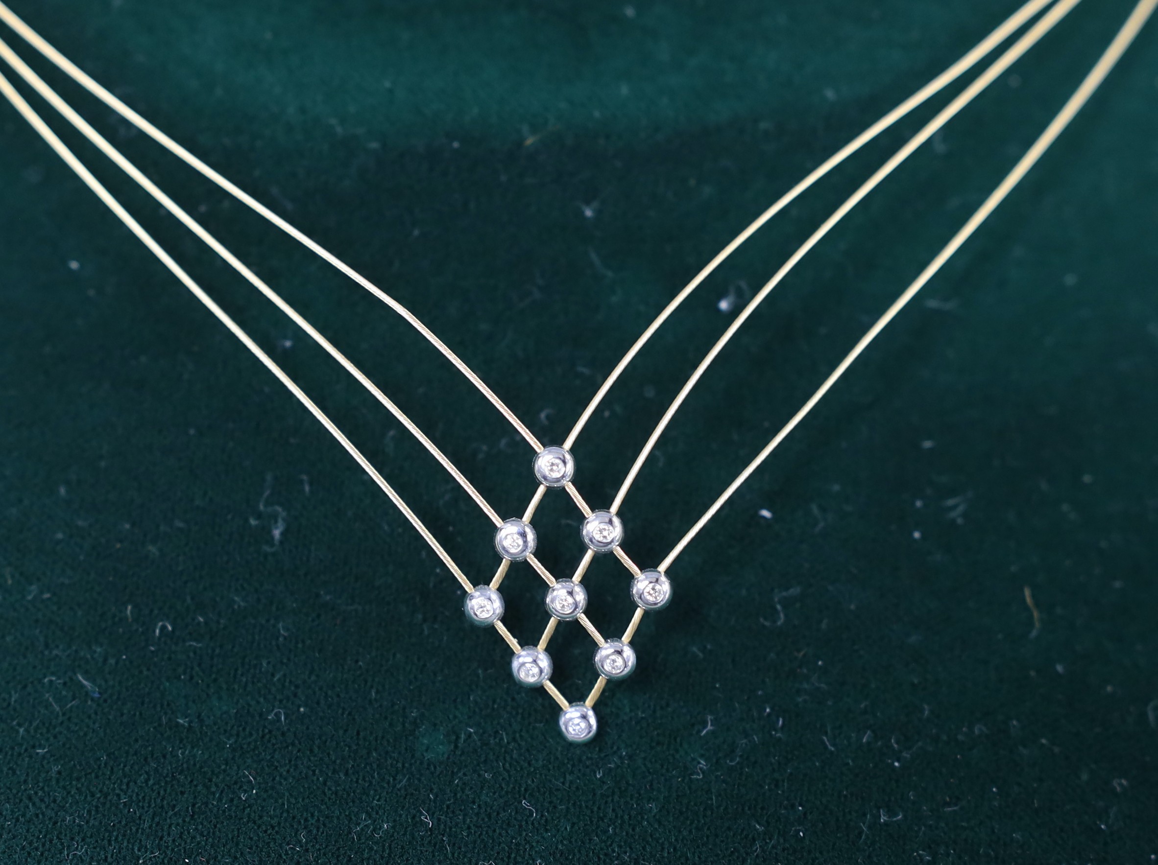 A boxed modern 18ct gold and nine stone diamond chip set triple fine strand necklet, approx. 42cm, gross weight 6 grams.